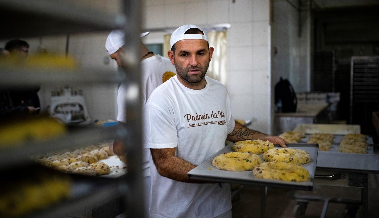Seorang tukang roti menyiapkan beberapa Bolo Rei atau Kue Raja untuk oven di toko roti Padaria da Ne, Amadora, Portugal, 16 Desember 2022. Memiliki bentuk cincin, kue ini memiliki banyak potongan buah beri dan kacang-kacangan seperti almond dan walnut. (CARLOS COSTA/AFP)
