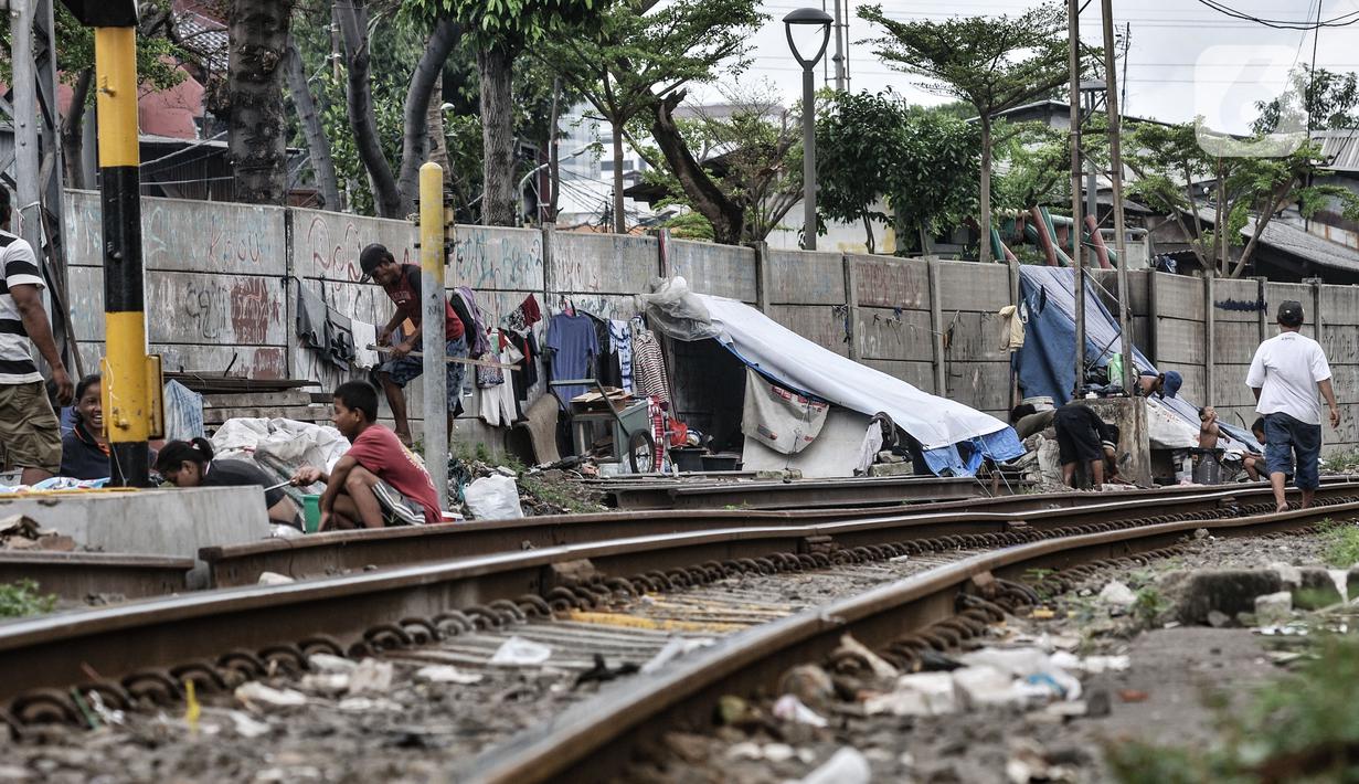 Sejumlah tunawisma beraktivitas di dekat gubuknya yang berada di bantaran rel kereta api kawasan Senen, Jakarta, Minggu (14/2/2021). Setelah sempat ditertibkan, puluhan bangunan semipermanen yang beratapkan terpal dan beralas kardus milik tunawisma kembali menjamur. (merdeka.com/Iqbal S. Nugroho)