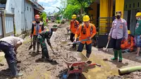 Petugas membersihkan lumpur sisa banjir di Jember. (Dian Kurniawan/Liputan6.com)