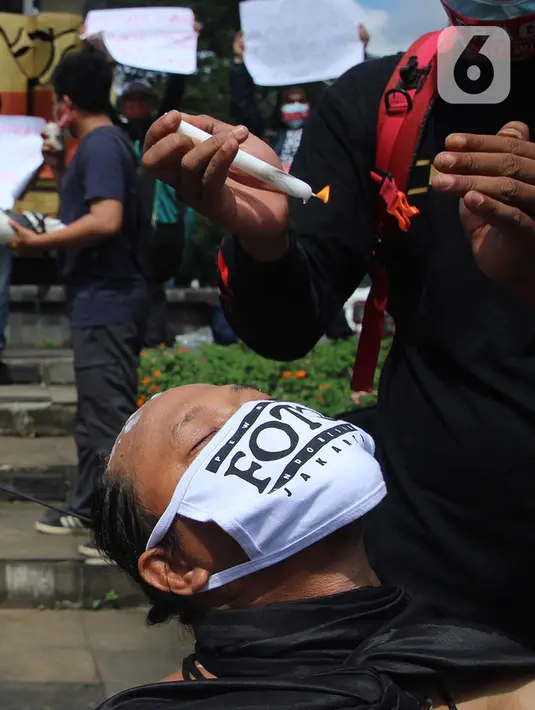 Seorang jurnalis melakukan aksi teatrikal saat aksi solidaritas di kawasan Tugu Adipura, Kota Tangerang, Rabu (31/3/2021). Mereka menuntut pihak berwenang mengusut tuntas oknum pelaku kekerasan terhadap wartawan Tempo, Nurhadi dan kasus kekerasan jurnalis lainnya. (Liputan6.com/Angga Yuniar)