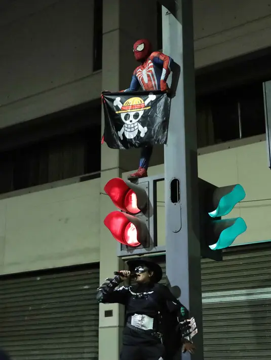 Tampak salah satu pengunjuk rasa berpakaian ala spiderman sambil mengusung bendera komik Jepang, One Piece, dalam aksi mereka di Lima, Peru pada 28 September 2025 waktu setempat. (CONNIE FRANCE/AFP)