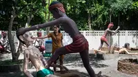 Para pengunjung melihat patung-patung yang menggambarkan nasib orang-orang yang tidak menjunjung tinggi lima ajaran Buddha di sebuah taman yang menggambarkan neraka versi Buddha di kuil Wat Saeng Suk di provinsi pantai Thailand Chonburi (9/7/2020). (AFP/Lillian Suwanrumpha)