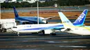 Pesawat charter (tengah) yang membawa warga Jepang dari Wuhan, China, mendarat di bandara internasional Haneda di Tokyo, Rabu (29/1/2020). Pesawat sewaan tersebut membawa pulang 206 warga negara Jepang dari Wuhan, pusat wabah virus corona. (AP/Eugene Hoshiko)
