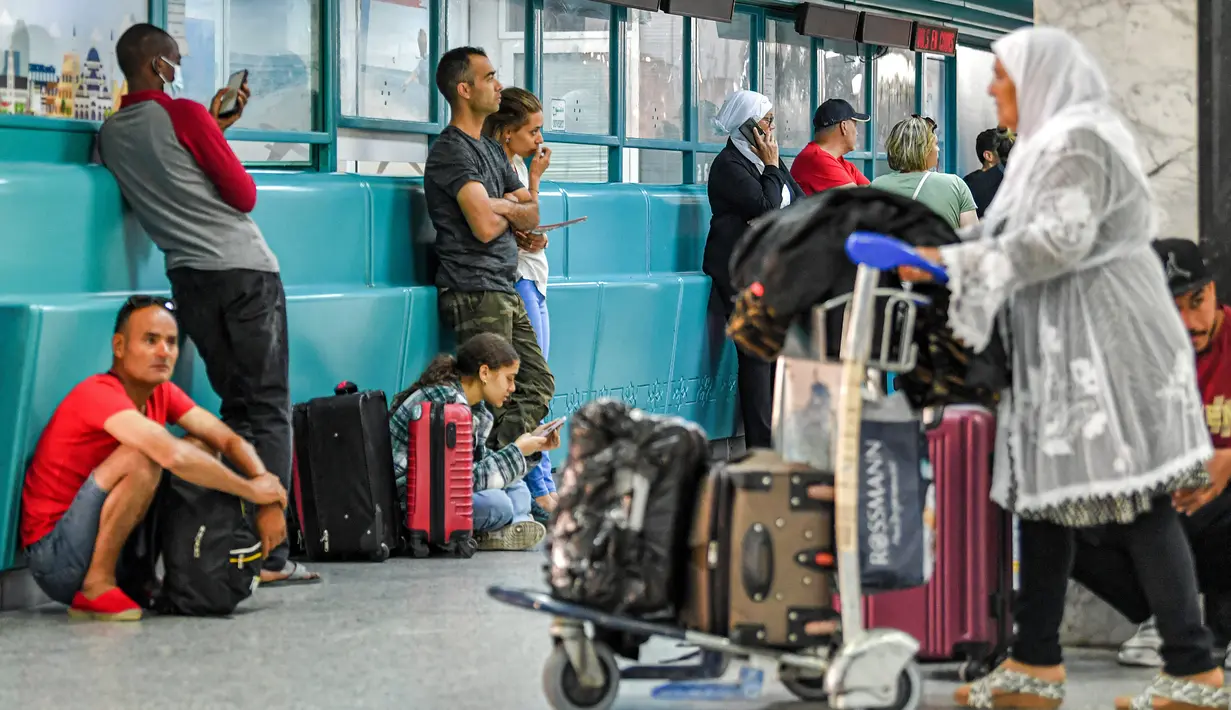 Wisatawan menunggu dengan barang bawaan mereka setelah penerbangan dibatalkan karena aksi mogok massal pekerja di Bandara Internasional Tunis-Carthage Tunisia, Kamis (16/6/2022). Serikat Pekerja Umum Tunisia (UGTT) mengadakan aksi mogok massal pada hari Kamis ini menuntut kenaikan gaji dan konsesi. (FETHI BELAID / AFP)
