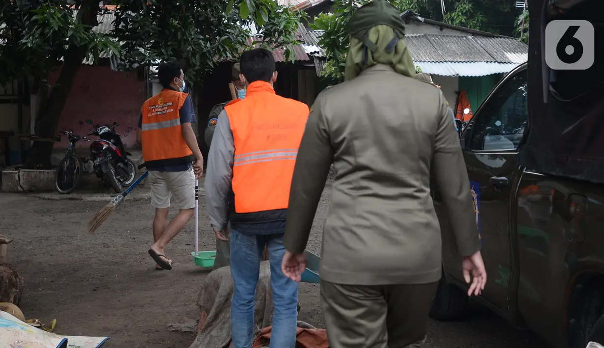 Anggota Satpol PP menghukum warga untuk menyapu jalan saat razia penggunaan masker di Kebon Nanas, Jakarta, Selasa (15/6/2021). Saat kasus positif Covid-19 di Jakarta meningkat, masih banyak warga yang belum menjalankan protokol kesehatan, salah satunya mengenakan masker. (merdeka.com/Imam Buhori)