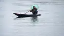 Seorang awak perahu Kashmir mengangkut penumpang saat hujan di Danau Dal di Srinagar (20/3). (AFP Photo/Tauseef Mustafa)
