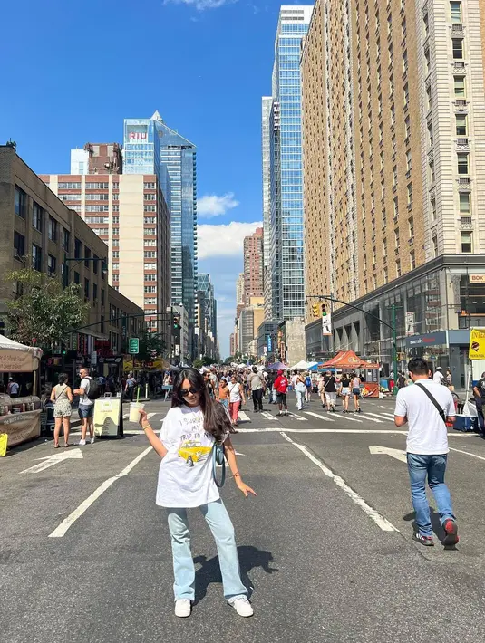 Beby Tsabina tampil kenakan oversized t-shirt berwarna putih. T-shirt bermotif ini dipadukan oleh Beby Tsabina dengan celana jeans, sneakers putih, dan sunglasses. Foto: Instagram.