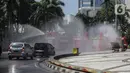 Mobil pemadam dari Dinas Pemadam Kebakaran Pemprov DKI melakukan penyemprotan cairan disinfektan di Jalan Thamrin, Jakarta, Selasa (31/3/2020). Penyemprotan yang dilakukan terus menerus itu untuk meminimalisir penyebaran COVID-19 di ruang udara dan ruas jalan. (Liputan6.com/Faizal Fanani)