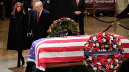 Presiden AS, Donald Trump dan Melania Trump saat akan memberikan penghormatan terakhir kepada George HW Bush di Gedung Capitol, Washington, Senin (3/12). Bush senior meninggal pada Jumat, 30 November 2018, di usia 94. (Pablo MARTINEZ MONSIVAIS/POOL/AFP)