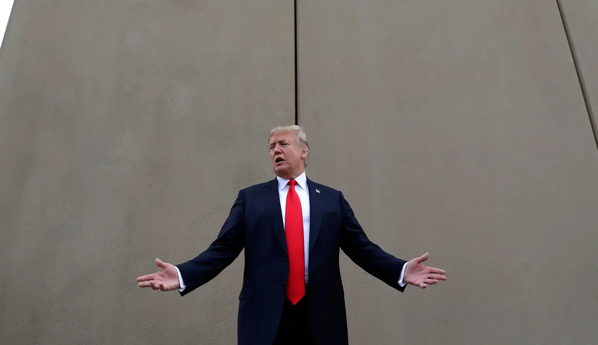 Presiden AS, Donald Trump berbincang saat melakukan perjalanan untuk melihat prototipe tembok perbatasan AS dan Meksiko di San Diego, Selasa (13/3). Tembok ini adalah perwujudan dari janji Trump pada kampanye presiden 2016 lalu. (AP/Evan Vucci)