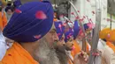 Umat Sikh yang dikenal sebagai 'Panj Pyare' memegang pedang selama prosesi keagamaan dari Gurudwara Ramsar ke Akal Takht Sahib di Kuil Emas, Amritsar, India, Rabu (19/8/2020). Acara ini untuk memperingati 416 tahun pelantikan Guru Granth Sahib. (NARINDER NANU/AFP)