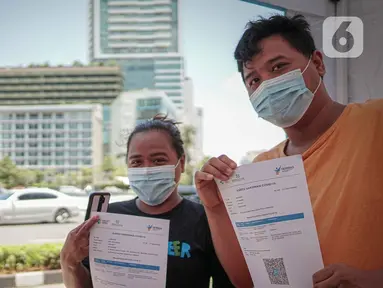 Warga menunjukkan kartu vaksinasi COVID-19 di Gerai Vaksinasi Presisi, Bundaran HI, Menteng, Jakarta, Minggu (20/3/2022). Kegiatan vaksin booster tersebut diinisasi Polsek Menteng bersama tiga pilar menggunakan jenis vaksin Astra Zeneca dengan kuota 100 dosis per hari. (Liputan6.com/Faizal Fanani)