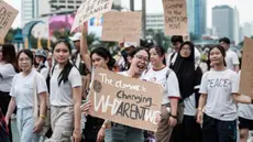 Para peserta memegang plakat saat mereka berbaris di jalan menjelang Hari Bumi pada 22 April, hari kesadaran lingkungan tahunan, di Jakarta pada 21 April 2024. (Yasuyoshi CHIBA/AFP)