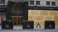 Seorang perempuan melewati Saks Fifth Avenue yang dipasangi papan pelindung di Fifth Avenue di New York, Amerika Serikat pada 1 November 2020. Langkah itu dilakukan saat para peretail berupaya melindungi properti dari penjarahan atau kerusuhan lainnya dalam beberapa hari mendatang (Xinhua/Wang Ying)