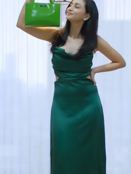 Valerie Tifanka mengenakan dress panjang berbahan sutra yang mengkilap dan menenteng tas Kate Spade. Ia terlihat membawa Sam Icon Small Tote berwarna Kate Spade Green dari bahan kulit spazzolato dan bersiluet simpel. Foto: Document/Kate Spade New York.