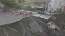 Petugas pemadam kebakaran memeriksa kondisi tanah amblas di Jalan Raya Gubeng, Surabaya, Rabu (19/12). Salah satu akses utama di Kota Surabaya itu amblas diduga karena proyek pembangunan gedung di sekitar lokasi (Liputan6.com/Pool/FB Dishub Kota Surabaya)