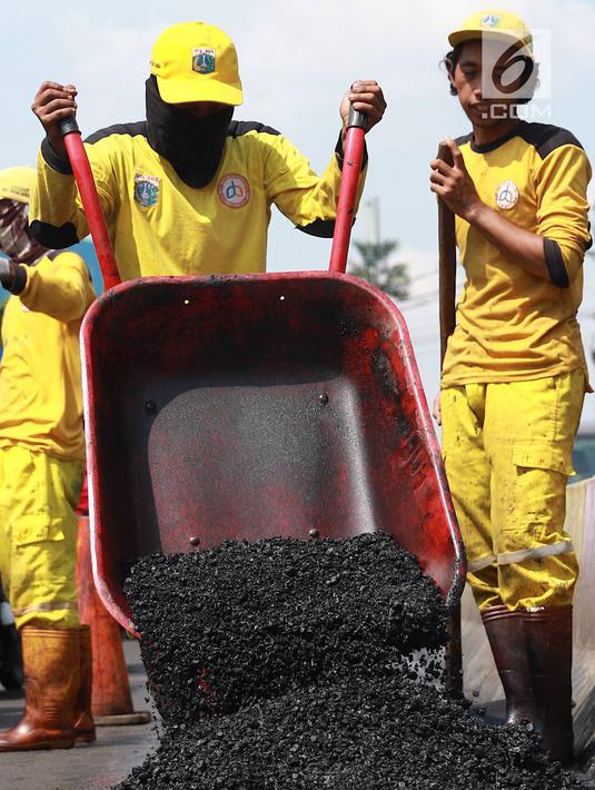 Petugas Bina Marga Pasar Minggu menambal jalan yang rusak di Jalan Raya Ragunan, Jakarta, Senin (22/4). Petugas mengaku bahwa keberadaan beton pembatas jalan justru membuat jalan di kawasan tersebut selalu rusak setiap hujan deras karena menimbulkan genangan air. (Liputan6.com/Immanuel Antonius)