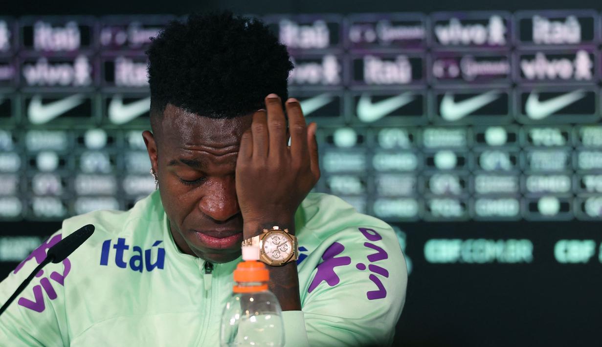 Pemain Brasil, Vinicius Jr menyeka air mata saat konferensi pers menjelang laga persahabatan melawan Spanyol di tempat latihan Ciudad Real Madrid di Valdebebas, pinggiran Madrid, pada 25 Maret 2024. Laga tersebut memiliki slogan "Satu Kulit" untuk membantu memerangi rasisme. (AFP/Pierre-Philippe Marcou)