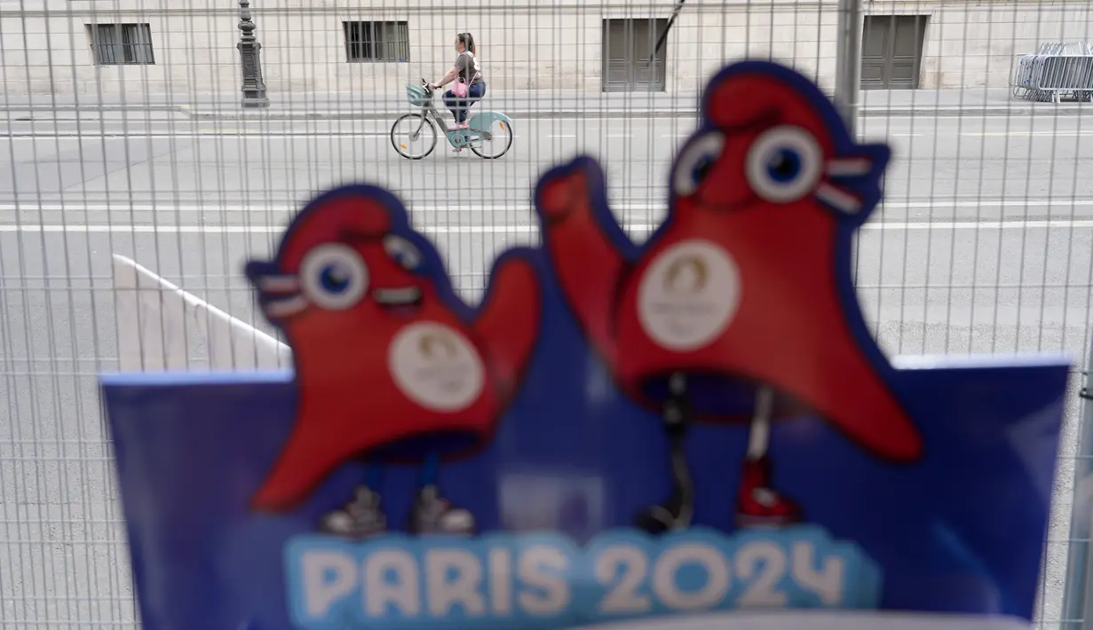 Seorang berkendara dengan sepeda di luar perimeter keamanan yang disiapkan untuk Olimpiade di Paris, Kamis (18/7/2024). (AP Photo/David Goldman)