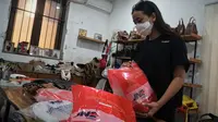 Pendiri Kaynn Craft Meyta Retnayu Lestari merapikan tas kulit yang akan dikirim ke pelanggan menggunakan jasa pengiriman JNE di ruang kerjanya di kawasan Gudang Selatan No 22, Kota Bandung, Kamis (23/12/2021). (Foto: Liputan6.com/Huyogo Simbolon)