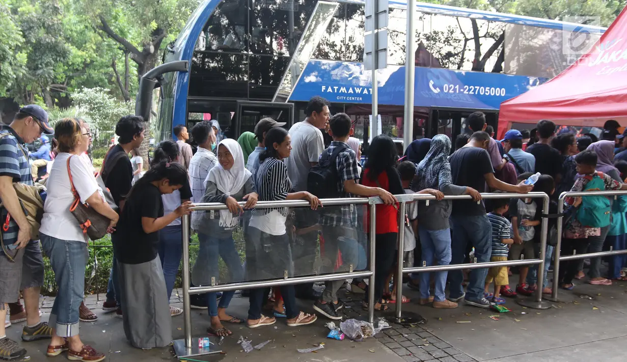 Warga antre untuk menaiki bus tingkat wisata keliling Ibu Kota di kawasan Monas, Jakarta, Sabtu (16/6). Libur Hari Raya Idul Fitri dimanfaatkan oleh sebagian masyarakat Jakarta untuk berlibur ketempat wisata bersama keluarga. (Liputan6.com/Arya Manggala)