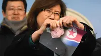 Seorang wanita yang membelot merobek foto pemimpin Korea Utara Kim Jong-Un saat konferensi pers di Majelis Nasional di Seoul (24/1). (AFP Photo/Jung Yeon-Je)