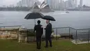 <p>Jokowi dan Anthony Albanese sama-sama menggunakan payung berwarna hitam untuk melindungi diri dari hujan yang turun. (Lisa Maree Williams/Pool via AP)</p>