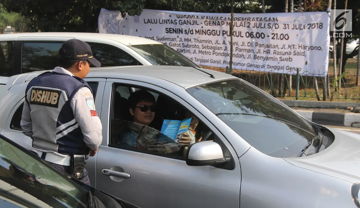 Petugas Dishub DKI membagikan brosur sosialisasi perluasan ganjil genap pada hari pertama uji coba di kawasan Tomang, Jakarta, Senin (2/7). Perluasan diberlakukan di ruas jalan yang terdapat arena pertandingan Asian Games. (Liputan6.com/Arya Manggala)