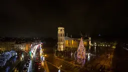 Pohon Natal Nasional dinyalakan selama upacara penyalaan di alun-alun Katedral di Vilnius, Lithuania pada 28 November 2020. Pohon natal raksasa yang dihiasi berbagai ornamen lampu hias tersebut membuat kawasan di ibu kota Lithuania menjadi terang. (AP Photo/Mindaugas Kulbis)