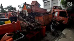 Petugas melakukan pengecekan bangkai armada truk sampah di Kantor Suku Dinas Lingkungan Hidup, Jakarta Barat, Selasa (27/3). Sebanyak 30 armada truk sampah diparkir dengan cara ditumpuk. (Liputan6.com/JohanTallo)
