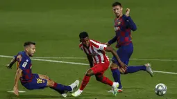 Pemain Atletico Madrid Thomas Lemar (tengah) mencoba melewati pemain Barcelona Jordi Alba (kiri) dan Clement Lenglet (kanan) pada pertandingan La Liga di Stadion Camp Nou, Barcelona, Spanyol, Selasa (30/6/2020). Barcelona bermain imbang 2-2 melawan Atletico Madrid. (AP Photo/Joan Monfort)