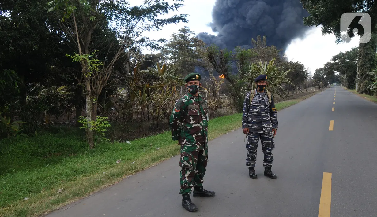 Anggota TNI berjaga di lokasi terbakarnya kilang minyak di Jalan Raya Balongan-Indramayu, Kabupaten Indramayu, Jawa Barat, Senin (29/3/2021).  Dampak dari terbakarnya kilang minyak Balongan milik PT Pertamina itu mengakibatkan Jalan Raya Balongan-Indramayu ditutup total. (merdeka.com/Arie Basuki)