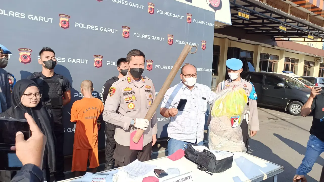 Kapolres Garut AKBP Wirdhanto Hadicaksono dan Kasatreskrim AKP Dede Sopandi menunjukan barang bukti sebilah besi yang digunakan dalam pembunuhan karyawan pabrik tahu. (Liputan6.com/Jayadi Supriadin)
