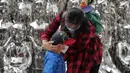 Seorang wanita membantu seorang anak mengenakan masker untuk mengekang penyebaran COVID-19 di Beijing, China, Minggu (11/10/2020). Meski penyebaran COVID-19 hampir diberantas di China, pandemi masih melonjak di seluruh dunia dengan jumlah kematian yang terus meningkat. (AP Photo/Andy Wong)
