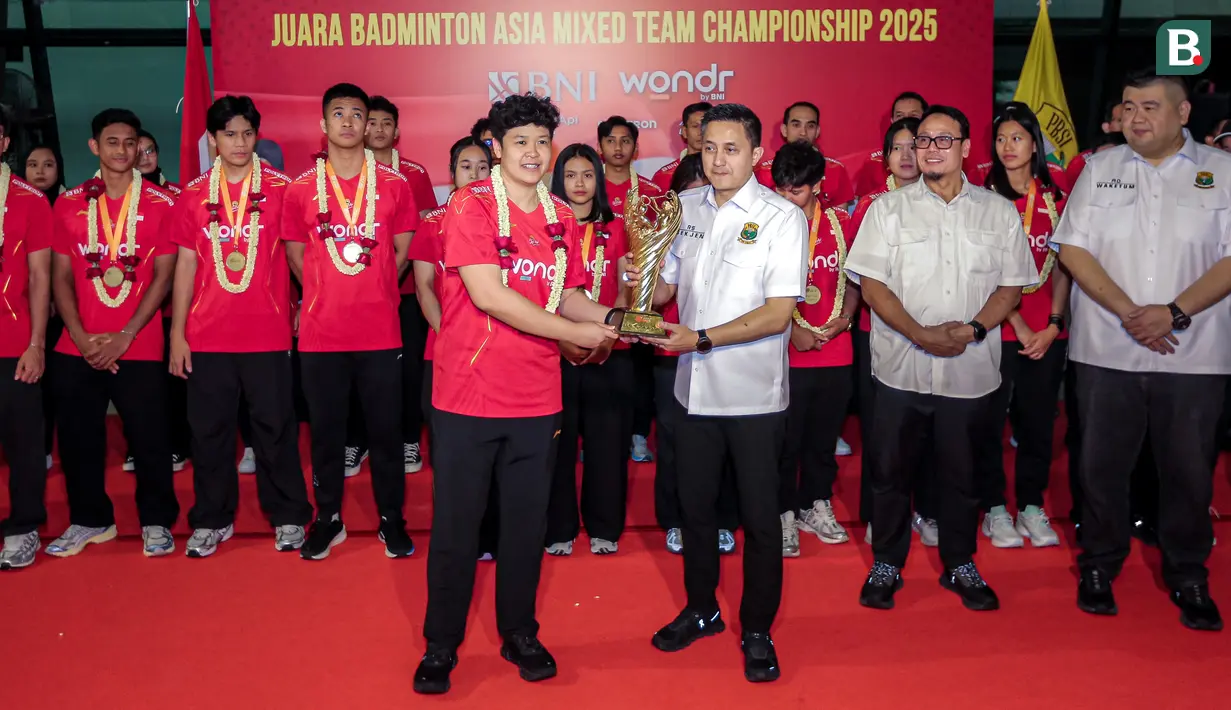 <p>Manajer Tim Bulu Tangkis Indonesia Shendy Puspa (tengah kiri) menyerahkan trofi Badminton Asia Mixed Team Championships 2025 kepada Sekretaris Jenderal PBSI, Ricky Soebagja (tengah kanan) saat penyambutan tim bulu tangkis Indonesia di Terminal 3 Bandara Soekarno Hatta, Tangerang, Senin (17/02/2025). (Bola.com/Bagaskara Lazuardi)</p>