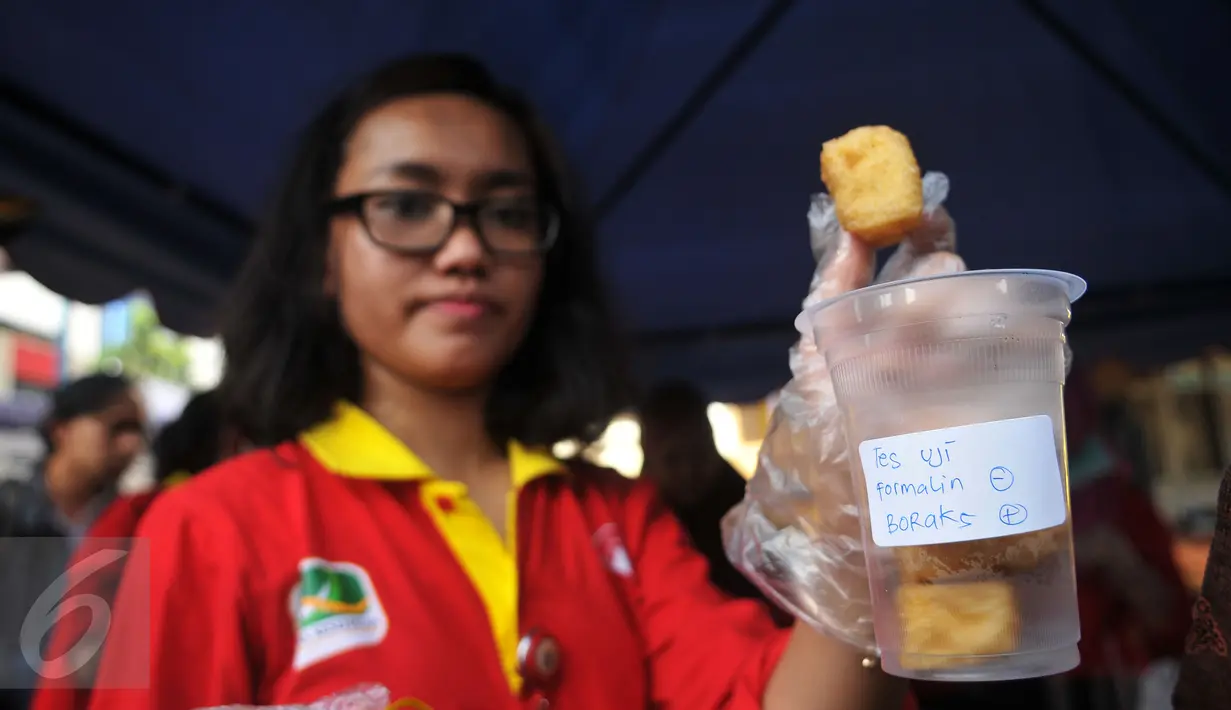 Petugas menunjukan temuan tahu berboraks saat inspeksi mendadak makanan berbuka puasa atau takjil di Bendungan Hilir, Jakarta, (10/6). Pedagang yang melakukan kecurangan akan diberi sangsi tegas untuk tidak berjualan. (Liputan6.com/Gempur M Surya)