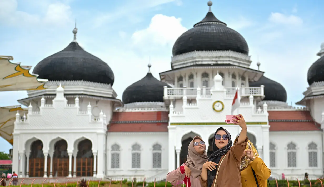 <p>Sejumlah wisatawan memadati halaman Masjid Raya Baiturrahman saat libur lebaran Idulfitri 1444 H di Banda Aceh, Aceh, Selasa (25/4/2023). (AFP/CHAIDEER MAHYUDDIN)</p>