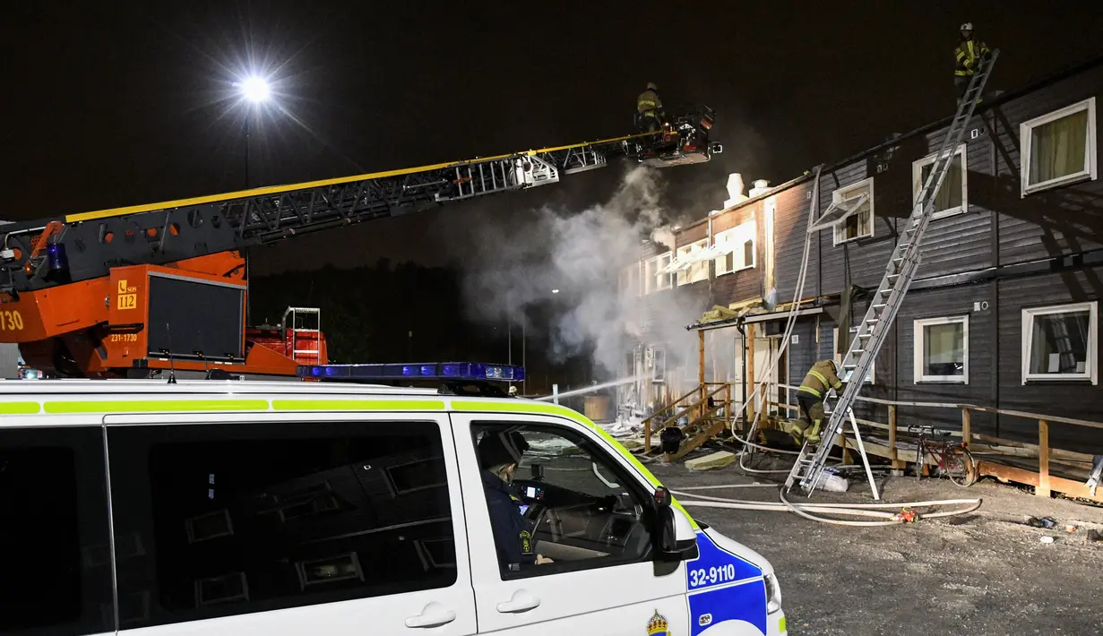 Petugas pemadam menggunakan mobil tangga saat berusaha memadamkan api yang membakar tempat pengungsian di Fagersjo, Stockholm, Swedia pada Minggu (16/10) malam. (REUTERS/TT News Agency / Johan Nilsson)