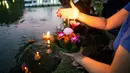 Seorang wanita bersiap menghayutkan 'krathong' untuk merayakan festival Loy Krathong di sebuah danau di Bangkok, Kamis (22/11). Loy Krathong adalah ritual melarung wadah berbentuk lotus yang didalamnya diberi sesajen, lilin dan dupa (Jewel SAMAD/AFP)