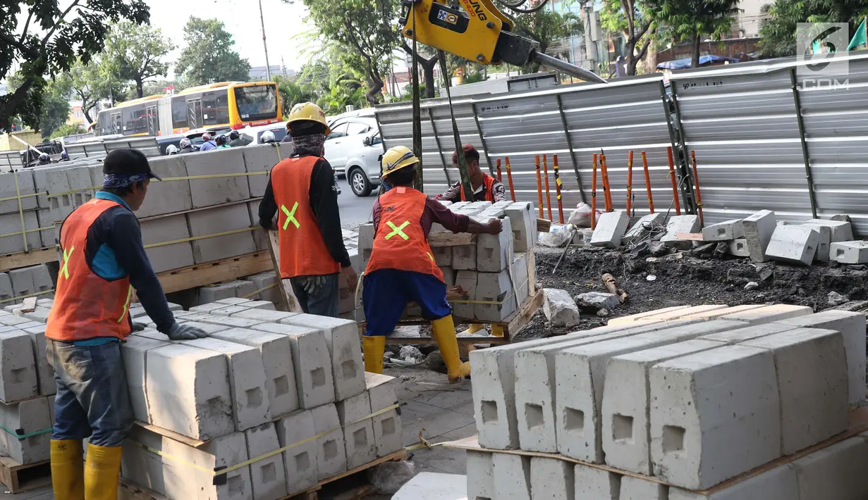 Aktivitas pekerja menyelesaikan proyek revitalisasi trotoar di Jalan Salemba Raya, Jakarta, Jumat (6/9/2019). Proyek revitalisasi trotoar dengan anggaran Rp 75 miliar ini ditargetkan rampung pada Desember mendatang. (Liputan6.com/Helmi Fithriansyah)