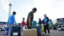 Angka ini meningkat dari target awal sekitar 30.774 orang karena tingginya antusiasme warga. Tampak dalam foto, orang-orang membawa barang-barang mereka saat tiba untuk perjalanan mudik gratis yang diselenggarakan oleh Pemerintah Provinsi Jakarta di Lapangan Monumen Nasional, Selasa 17 Maret 2026. (AP Photo/Achmad Ibrahim)