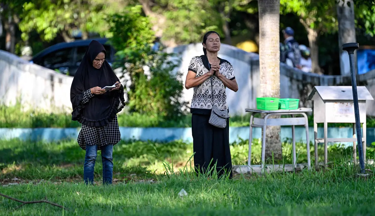 Bencana yang dipicu gempa bumi berkekuatan magnitudo 9,1 itu tercatat sebagai salah satu tragedi paling mematikan dalam sejarah modern. Lebih dari 200 ribu jiwa melayang, ribuan infrastruktur vital hancur lebur, dan roda perekonomian Aceh kala itu nyaris lumpuh total. Tampak dalam foto, orang-orang berdoa untuk kerabat mereka yang kehilangan nyawa dalam peristiwa gempa dan tsunami Aceh pada 2004 lalu di sebuah kuburan massal di Siron, pada 26 Desember 2025. (CHAIDEER MAHYUDDIN/AFP)