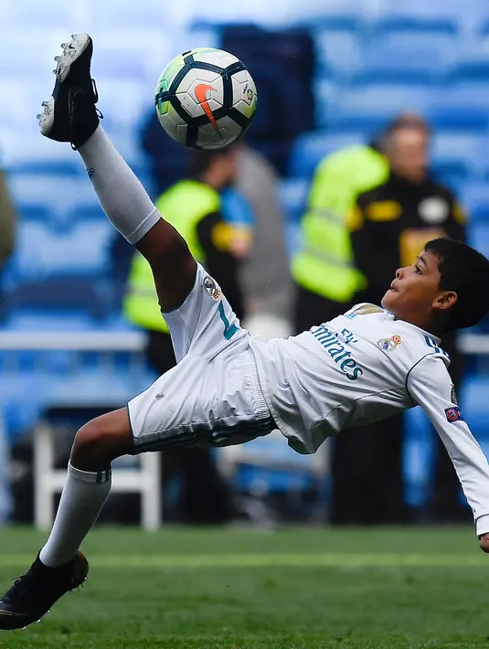 Anak Cristiano Ronaldo, Cristiano Ronaldo Jr melakukan tendangan salto usai pertandingan antara Real Madrid dan Atletico Madrid di stadion Santiago Bernabeu, Madrid (8/4). Anak Ronaldo melakukan tendangan salto meniru sang ayah. (AFP Photo/Gabriel Bouys)