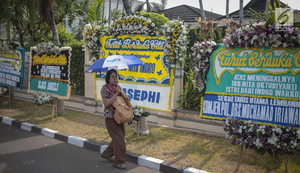 Warga melintas dekat karangan bunga atas meninggalnya istri Indro Warkop, Nita Octobijanthy yang terpajang di rumah duka kawasan Pulo Mas, Jakarta, Rabu (10/10). Istri Indro Warkop meninggal di usia 59 tahun akibat kanker. (Liputan6.com/Faizal Fanani)