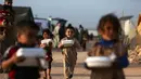 Anak-anak Suriah kembali ke tenda mereka dengan kotak-kotak makanan yang didistribusikan organisasi amal lokal, sebelum berbuka puasa selama bulan suci Ramadhan di kamp pengungsi di pinggiran kota Dana yang dikuasai pemberontak, timur perbatasan Turki-Suriah di Idlib (3/4/2022). (AFP/Aaref Watad)