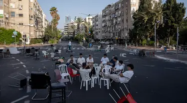 Sejumlah pemuda duduk bersama di persimpangan jalan bebas kendaraan saat perayaan Hari Raya Yom Kippur di Ramat Gan, Israel, Senin (25/9/2023). Banyak warga yang menggunakan sepeda ke jalan karena tidak ada lalu lintas yang diizinkan di jalan tersebut. (AP Photo/Oded Balilty)