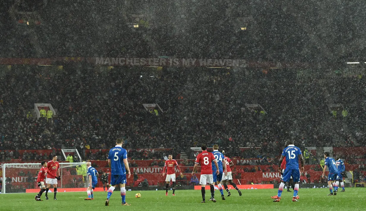 Kucuran hujan turun di tengan laga pekan ke-23 Premier League 2017-2018 antara Manchester United melawan Stoke City di Old Trafford, Senin (15/1). Bermain di kandang sendiri, Manchester United menuntaskan permainan dengan skor 3-0. (Oli SCARFF/AFP)