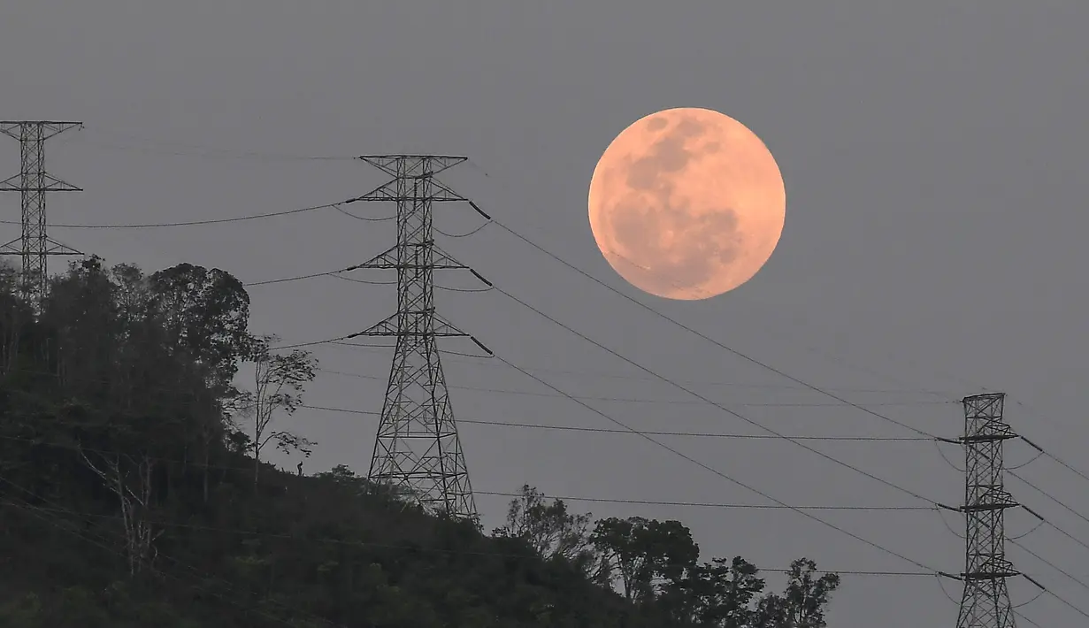 Bulan purnama muncul di balik menara tegangan tinggi El Avila di Caracas, Venezuela, Minggu (15/5/2022). Orang-orang di Amerika, Eropa, dan Afrika akan menyaksikan gerhana bulan total pada malam tanggal 15-16 Mei. (AP Photo/Matias Delacroix)