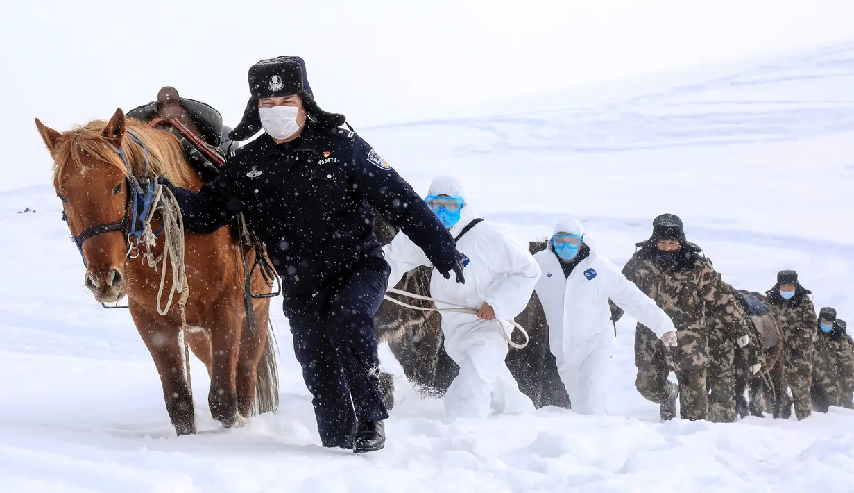 Petugas polisi mengenakan masker wajah saat melakukan perjalanan menantang saat akan mengunjungi rumah-rumah penduduk di daerah terpencil di Altay, Wilayah Xinjiang, China (19/2/2020). (AFP/STR)