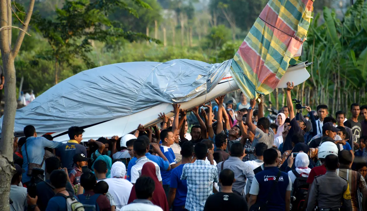 Warga mengevakuasi pesawat Shark Aero PK S 121 yang dipiloti gubernur Aceh, Irwandi Yusuf seusai mendarat darurat di kawasan Ujong Pancu, Aceh Besar, Sabtu ( 17/2). Belum diketahui penyebab pesawat tersebut harus mendarat darurat. (CHAIDEER MAHYUDDIN/AFP)